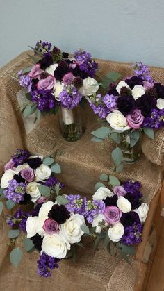 three vases filled with purple and white flowers on top of a burlock