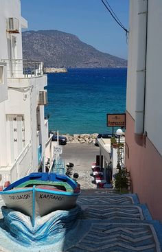 a boat that is sitting on the ground in front of some buildings by the water