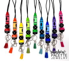 several different colored crayons with black beads and tassels hanging from them