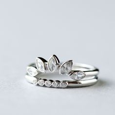 three silver rings with white stones on them sitting on top of each other in front of a gray background