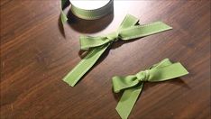 two green bows are sitting on a table next to a cup with a candle in it