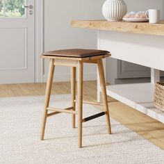 a wooden stool sitting on top of a white rug in front of a countertop