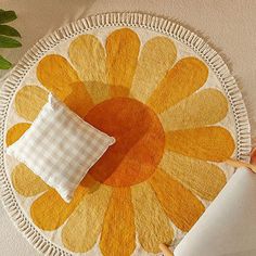 a yellow and white flower rug on the wall next to a toilet paper holder with a roll of toilet paper in front of it