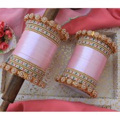 two pink bracelets sitting on top of a table next to a vase with flowers