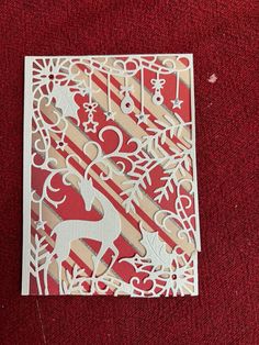 a piece of paper cut out to look like a deer and snowflakes on a red background