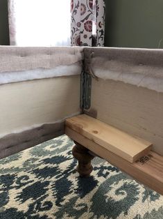 a wooden bench sitting on top of a blue and white rug next to a window