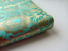 a close up of a blue and gold fabric with an intricate design on the side