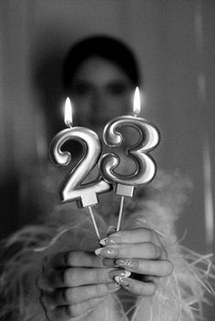 a woman holding two candles with the number twenty eight on them in front of her face