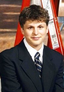 a young man in a suit and tie posing for a photo with his arms crossed