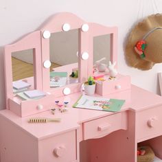 a pink vanity with mirror and lights on it in a child's playroom