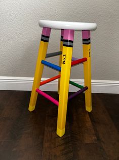 a stool made out of colored pencils sitting on top of a hard wood floor