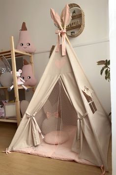 a teepee tent in the corner of a room with stuffed animals and other toys