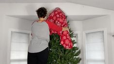 a man is hanging a christmas tree on the wall