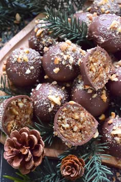 chocolate balls with nuts and pine cones on a wooden platter surrounded by evergreen branches