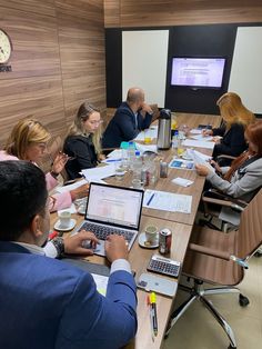 a group of people sitting at a table with laptops and papers in front of them