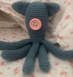 an octopus stuffed animal with a button on it's head sitting on a bed