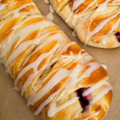 two croissants with white icing sitting on top of a table next to each other