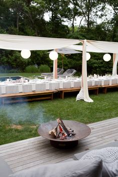 a fire pit sitting on top of a wooden deck next to a lush green field