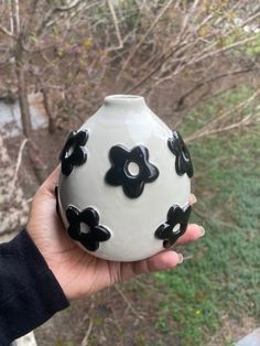 a hand holding a black and white vase