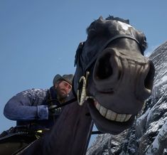 a man riding on the back of a horse next to a snow covered mountain side