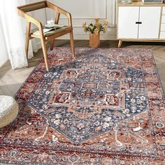 a large rug with an ornate design on the floor in front of a chair and sideboard