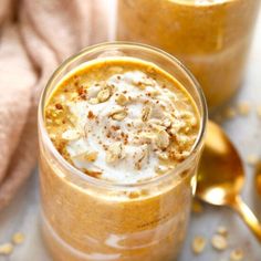 two jars filled with food sitting on top of a white table next to gold spoons