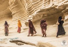 four women in colorful dresses walking through the desert