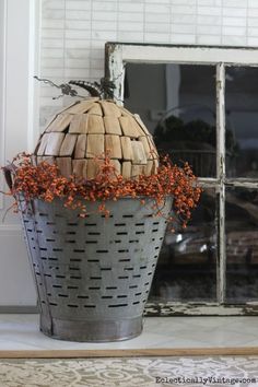 a large metal basket filled with red berries on top of a white tablecloth next to an old window