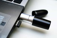 an open laptop computer sitting on top of a white table next to two black pens