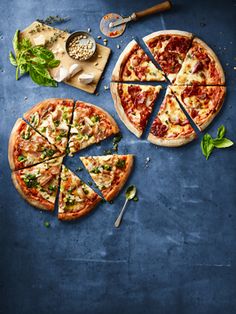 two pizzas cut into eight slices on top of a table next to a spatula