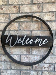 a welcome sign mounted to the side of a brick wall with a circular metal frame