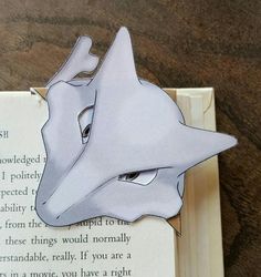 a book with a paper cut out of the face of a dragon on top of it