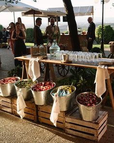 several buckets of fruit are on display at an outdoor market