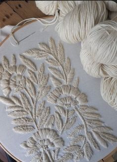 some white yarns are on a table and there is a plant in the middle