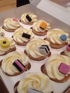 a box filled with cupcakes covered in white frosting and colorful icing