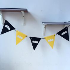 a batman themed party banner hanging on the wall with black and yellow pennants in front of it