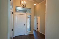 an empty entryway with two doors and a light fixture hanging from the ceiling above it