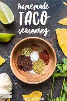 homemade taco seasoning in a wooden bowl surrounded by cilantro and limes