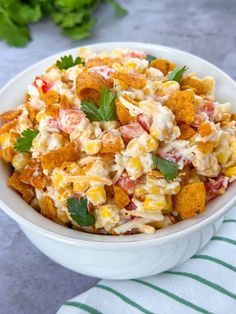 a white bowl filled with corn salad and garnished with parsley on top