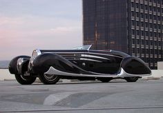 an antique car parked in front of a tall building