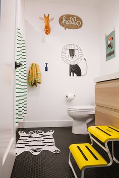 a bathroom with black and white flooring and yellow chairs in front of the toilet