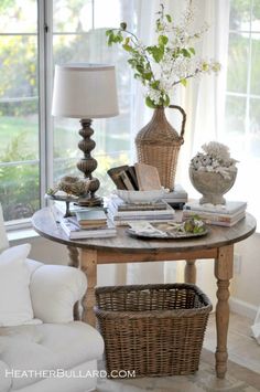 a living room filled with furniture and a table covered in books on top of a hard wood floor