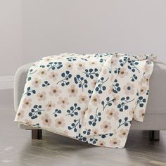 a couch with a blanket on top of it in front of a white wall and wooden floor