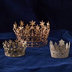 three gold crowns sitting on top of a blue cloth