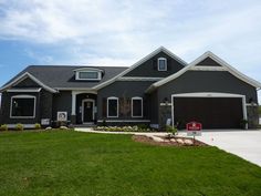 a gray house with two garages and green grass