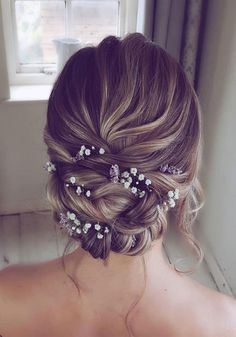 the back of a woman's head with flowers in her hair, looking out a window