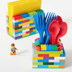 lego blocks and plastic utensils are in a box with a toy figure next to it