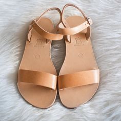 a pair of women's tan sandals sitting on top of a white fur rug