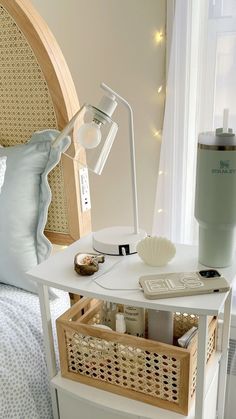 a white table topped with a lamp next to a bed