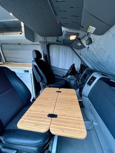 the interior of a van with wooden tables and seats